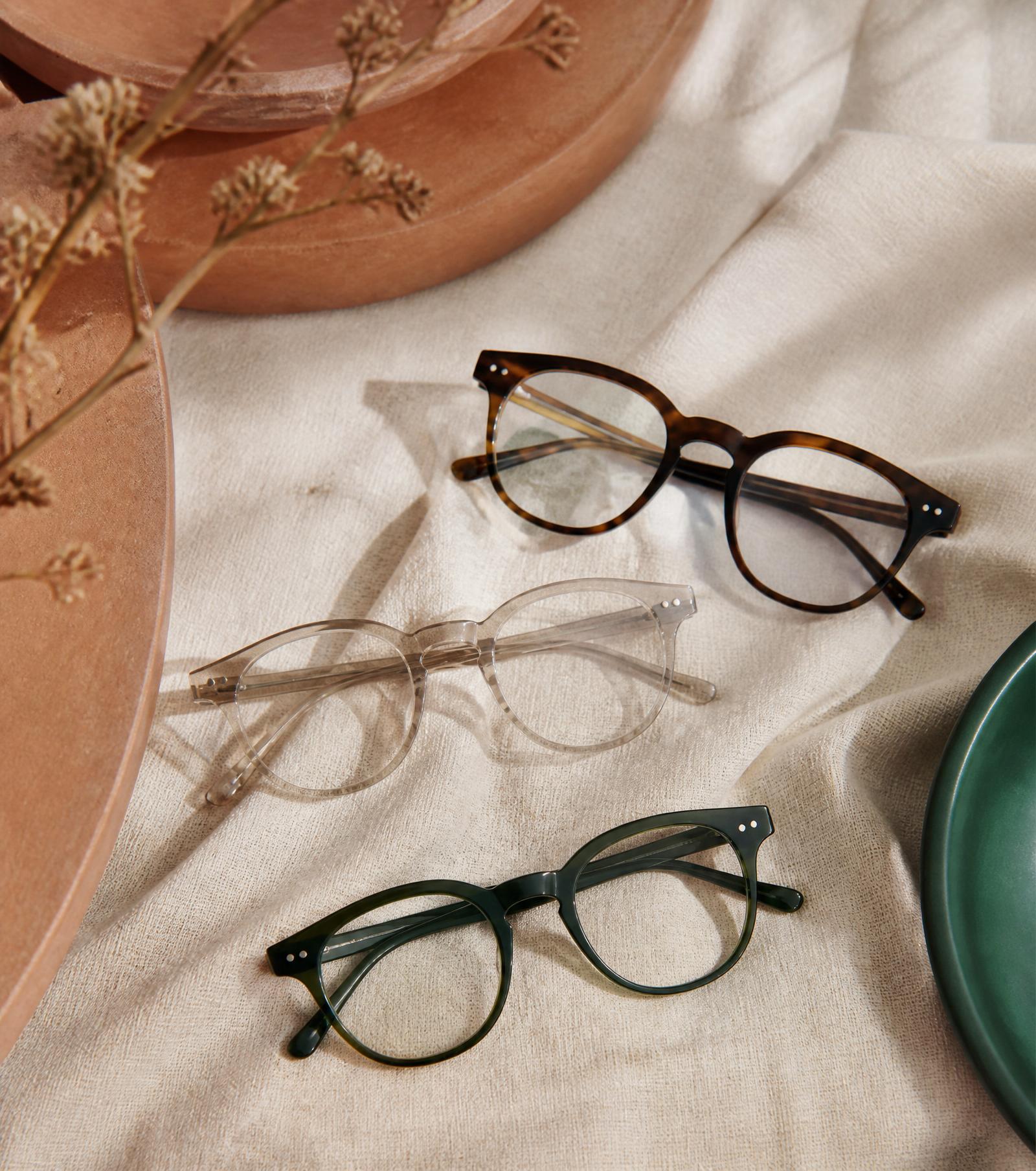 Montures de lunettes de créateurs présentées sur textile beige